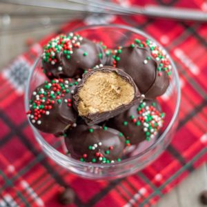 buckeyes with red and green sprinkles, in a clear bowl on a plaid tablecloth